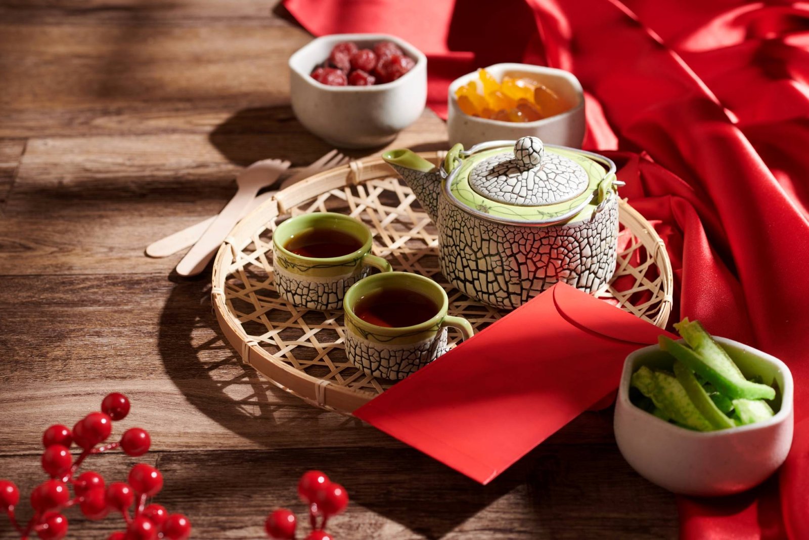 A round bamboo steamer basket filled with dumplings and small dishes, set on a wooden table with red festive decor and greenery, evoking a Lunar New Year or traditional tea-time spread.